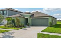 Single-story house with green exterior, two-car garage, and landscaped front yard at 13265 Great Plains Dr, Riverview, FL 33579
