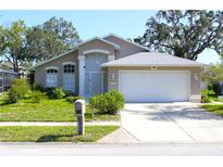 Charming single-story home featuring a well-maintained lawn and a two-car garage at 13451 Knotty Ln, Hudson, FL 34669