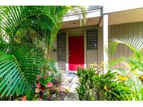 Red front door entrance with lush tropical landscaping at 758 Pine Run Dr # 758, Osprey, FL 34229