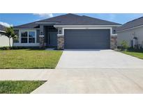 Charming single-story home showcasing a gray facade, stone accents, and a spacious two-car garage at 13260 Ogden Glade Rd, Dade City, FL 33525