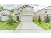 Two-story house with a two-car garage, landscaping, and driveway at 6355 Back Forty Loop, Zephyrhills, FL 33541