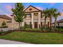Stunning two-story home featuring meticulously landscaped front yard, paired with a three car garage and lush palm trees at 33346 Kateland Dr, Wesley Chapel, FL 33545