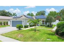 Single-story home with gray garage door and solar panels, landscaped yard at 4504 Horseshoe Pick Ln, Valrico, FL 33594