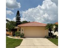 Tan house with tile roof, single car garage, and manicured lawn at 4115 Murfield E Dr, Bradenton, FL 34203
