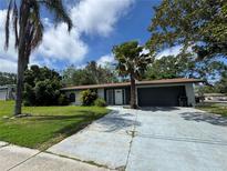 Charming single-story home with a well-maintained lawn and mature trees creating shade at 1920 N Highland Ave, Clearwater, FL 33755