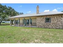 Inviting ranch-style home featuring a stone facade, metal roof, and charming porch at 8602 State Road 674, Wimauma, FL 33598