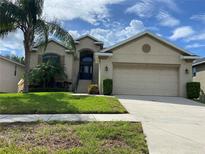 Beige house with two car garage and palm trees at 1134 S Pointe Alexis Dr, Tarpon Springs, FL 34689