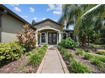 Inviting front entrance with stone accents, meticulously landscaped walkway, and double glass doors at 331 Star Shell Dr, Apollo Beach, FL 33572