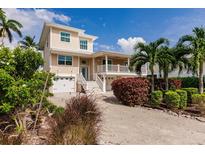 Beautiful two-story home with a beige exterior, white trim, and well-manicured landscaping with palm trees at 210 Lakeview Dr, Anna Maria, FL 34216