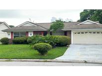 Ranch-style home with a two car garage and well-manicured lawn at 12107 Meadowbrook Ln, Hudson, FL 34667