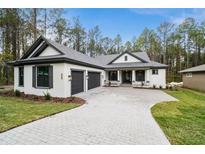 Two story home with gray and white exterior, two car garage, and paver driveway at 19411 Sheltered Hill Dr, Brooksville, FL 34601