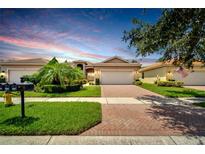 Two-story house with a brick driveway and landscaped front yard at 16216 Amethyst Key Dr, Wimauma, FL 33598