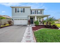 Two-story home with teal exterior, stone accents, and landscaping at 16632 Goose Ribbon Pl, Wimauma, FL 33598