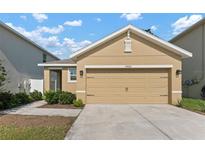 Tan house with a two car garage and landscaping at 10920 Carlton Fields Dr, Riverview, FL 33579