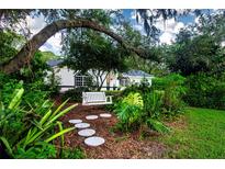 Charming house with a lush, landscaped front yard, featuring a white swing at 3111 Arrowsmith Rd, Wimauma, FL 33598
