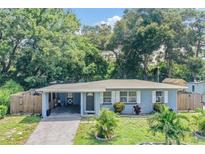 Charming single-story home with carport and front lawn, surrounded by lush trees and a partial fence at 1611 Stevenson Dr, Clearwater, FL 33755