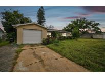 House exterior featuring a single car garage and a spacious front yard at 1240 Chelsea Ln, Holiday, FL 34691