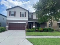 Two-story house with brown garage door and landscaping at 3015 Winglewood Cir, Lutz, FL 33558
