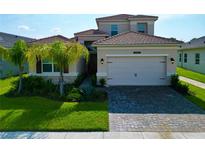 Two-story house with a beige exterior and a brick paver driveway at 32676 Tree Of Life Ave, Wesley Chapel, FL 33543