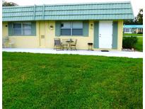 Front view of a yellow single-story home with green roof and small lawn at 102 Cambridge Trl # 230, Sun City Center, FL 33573