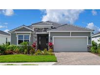 Charming one-story home with stone accents, gray siding, and a well-manicured lawn at 18142 Beach Ranch Ter, Lakewood Ranch, FL 34211