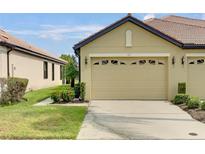 Tan villa with two-car garage, landscaping, and walkway at 227 Mystic Falls Dr, Apollo Beach, FL 33572