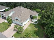 An aerial view of a well-maintained property with a brick driveway, manicured lawn and mature trees at 2309 Mooney. Pl, Sun City Center, FL 33573