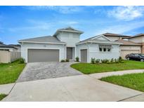 Two-story light blue house with gray double garage and paver driveway at 10520 Purple Thistle Way, San Antonio, FL 33576