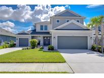 Two-story house with gray siding, two-car garage, and landscaped lawn at 2406 High Tides Way, Wesley Chapel, FL 33543