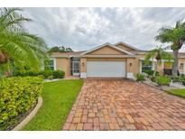 Tan one-story home with brick driveway and landscaping at 736 Mccallister Ave, Sun City Center, FL 33573