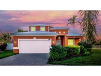 Charming two-story home featuring an attached garage, beautiful landscaping, and a colorful sunset backdrop at 6404 Key Island Ave, Apollo Beach, FL 33572