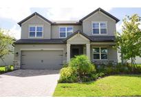 Two story home with gray siding and a three-car garage at 5776 Newberry Pines Ave, Wesley Chapel, FL 33545