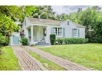 Charming bungalow with a brick driveway, lush lawn, and inviting front porch at 1411 E Powhatan Ave, Tampa, FL 33604