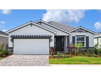 Beautiful single Gathering home showcasing a manicured lawn, dark trim and light colored walls at 18146 Beach Ranch Ter, Lakewood Ranch, FL 34211
