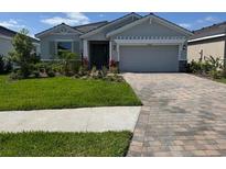 Charming one-story home with a manicured lawn and a brick-paved driveway leading to an attached two-car garage at 18204 Beach Ranch Ter, Lakewood Ranch, FL 34211