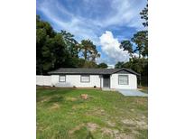 Newly renovated home with gray roof, white exterior, and landscaped yard at 4830 Capron St, New Port Richey, FL 34653