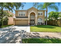 Two-story house with a tan exterior, two-car garage, and lush green lawn at 5707 Butterfield St, Riverview, FL 33578