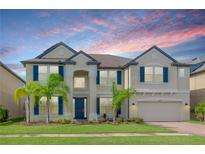 Two-story house with a neutral color palette, blue shutters, and palm trees at 10813 Rolling Moss Rd, Tampa, FL 33647