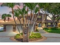 Brick house with three-car garage, palm trees, and circular driveway at 833 Ponce De Leon Dr, Tierra Verde, FL 33715