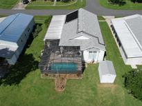 Aerial view of a home with a screened-in pool, solar panels, and a storage shed at 6036 Ridgeway Dr, Zephyrhills, FL 33542