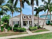 Charming home with a well-manicured lawn, lush landscaping, and inviting front porch, surrounded by palm trees at 617 Islebay Dr, Apollo Beach, FL 33572
