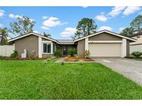 Single-story home with attached garage and well-maintained lawn at 15635 Bear Creek Dr, Tampa, FL 33624