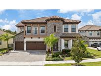 Two-story home with stone accents and a three-car garage at 13029 Paddock Wood Pl, Riverview, FL 33579