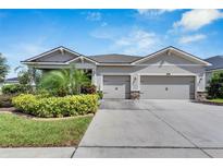 Single-story home with a three-car garage and landscaped front yard at 13012 Rain Lily Dr, Riverview, FL 33579