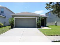 House exterior featuring a two-car garage and well-maintained landscaping at 11919 Grand Kempston Dr, Gibsonton, FL 33534