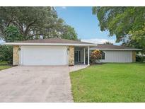 House exterior featuring a white garage door, stone accents, and a well-maintained lawn at 6605 Pointe West Blvd, Bradenton, FL 34209