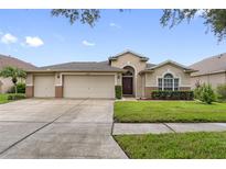 Tan two-story house with three car garage and landscaped yard at 18203 Collridge Dr, Tampa, FL 33647