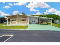 Mobile home with carport, landscaping, and American flag at 7048 El Meyers St, Zephyrhills, FL 33541