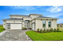 Elegant two-story home boasting a manicured lawn, paver driveway, and modern architectural details at 32252 Wetland Bird Vw, San Antonio, FL 33576
