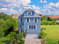 Charming three-story home features a paved driveway and a two-car garage in a serene residential setting at 6419 Marbella Blvd, Apollo Beach, FL 33572